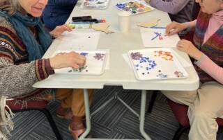 Participants arrange pieces of glass in a paper outline of a bird