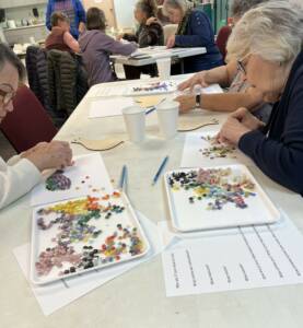 Participants arrange pieces of glass in a paper outline of a bird