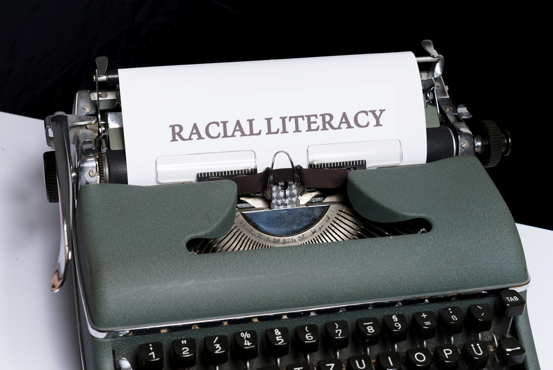 a typewriter with 'racial literacy' on the paper